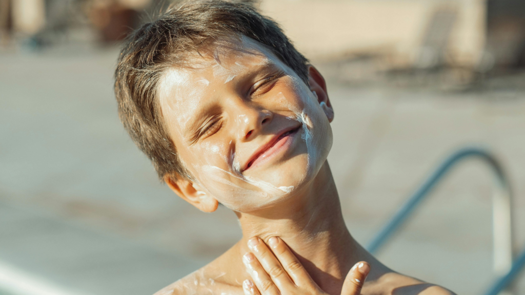 A person applying mineral sunscreen to their face with a focus on clear, healthy skin